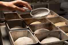 特写镜头女手洒一块生面团烘焙形式面粉准备面团烘焙面包工艺面包店
