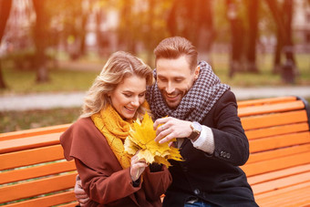 年轻的拥抱快乐浪漫的夫妇坐着轻轻拥抱板凳上公园穿外套围巾浪漫的夫妇坐着板凳上拥抱公园爱故事