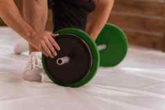 修复杠铃年轻的男人。弓膝盖添加黑色的绿色盘子设备重量培训概念体育设备培训重量损失健康的生活方式概念