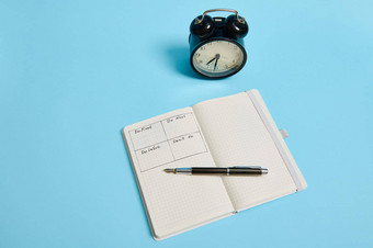 时间管理的最后期限概念适当的规划组织时间开放组织者笔记本时间表一天小时墨水笔报警时钟彩色的背景复制空间