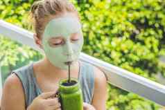 水疗中心女人应用面部绿色粘土面具美治疗新鲜的绿色奶昔香蕉菠菜心芝麻种子爱健康的生食物概念排毒概念