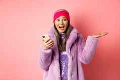 在线购物时尚概念女人检查太棒了促销提供智能手机尖叫快乐相机惊讶快乐脸粉红色的背景