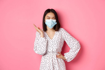 科维德检疫生活方式概念美丽的自信亚洲女人衣服脸面具自信的站时髦的粉红色的背景