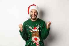 圣诞节假期庆祝活动聚会，派对概念快乐的家伙圣诞老人他毛衣使拳头泵欢乐并站白色背景