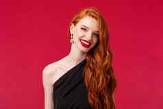 特写镜头肖像优雅的华丽的年轻的红色头发的人女人红色的口红晚上化妆耳环穿黑色的衣服喜气洋洋的微笑脸表达快乐幸福