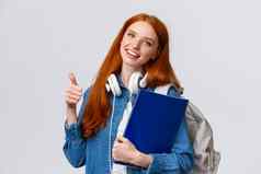 教育青少年学生生活方式概念快乐的红色头发的人可爱的女孩背包文件夹带投资组合艺术设计类显示翘拇指批准手势