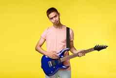 生活方式休闲青年概念悲观的亚洲的家伙玩乐队伤心不安坏一天持有电吉他学习仪器站黄色的背景