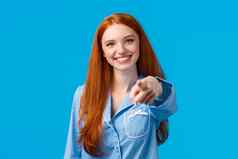 快乐的自信红色头发的人女孩使保证选择指出手指相机微笑决定挑选变体会说话的人站睡衣蓝色的背景