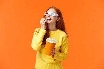 快乐逗乐红色头发的人女孩喜欢看电影剧院参加电影吃爆米花屏幕眼镜微笑进行有趣的电影橙色背景