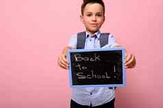 可爱的小学生背包持有黑板粉笔刻字回来学校孤立的粉红色的背景空间文本