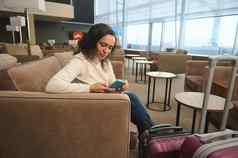 自信业务女人旅行坐着表格移动电话放松扶手椅豪华的休息室机场离开终端等待董事会飞行