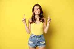 肖像快乐的女孩微笑指出手指显示促销文本夏天广告站黄色的背景