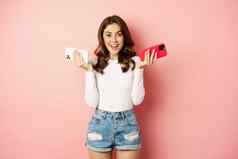 技术春天促销概念时尚的魅力女人持有智能手机移动手机手微笑很高兴购买手机粉红色的背景