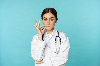 病人医生特权年轻的女人医疗保健工人显示口密封拉链手势站白色外套毙瑁背景