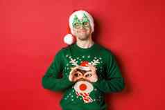 图像快乐微笑男人。聚会，派对眼镜圣诞老人他愚弄有趣的圣诞节毛衣庆祝冬天假期站红色的背景