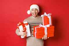 概念冬天假期一年庆祝活动图像快乐的家伙享受圣诞节持有桩礼物微笑逗乐站红色的背景