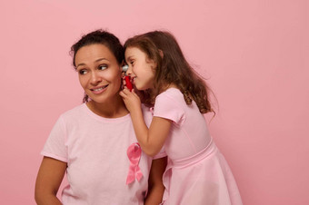 女孩玩医生妈妈。美丽的非洲美国女人婴儿女孩粉红色的粉红色的丝带象征国际乳房癌症意识一天医疗教育概念