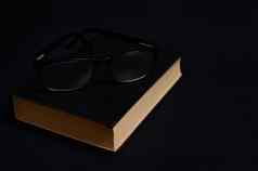 单色作文眼镜书硬黑色的封面孤立的黑色的背景复制空间老师的一天概念知识文学阅读博学