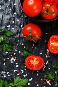 新鲜的切片樱桃西红柿黑色的背景香料粗盐草本植物
