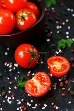 新鲜的切片樱桃西红柿黑色的背景香料粗盐草本植物