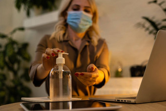 保护流感大流行疫情年轻的女人办公室喷涂消毒剂手医疗面具