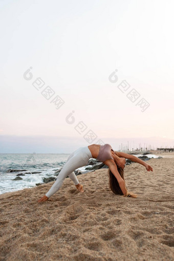 年轻的女人瑜伽海滩女实践野生事情瑜伽构成日落复制空间垂直图像