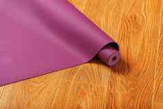 展开lilac-colored瑜伽席展开木地板上