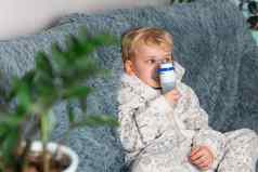 可爱的婴儿男孩使吸入喷雾器设备生病的孩子持有吸入器手呼吸吸入器首页