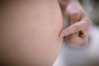 怀孕了女人肚子怀孕概念孤立的黑色的背景怀孕了肚子关闭手指指出肚子按钮