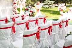 婚礼仪式在户外白色椅子红色的丝带