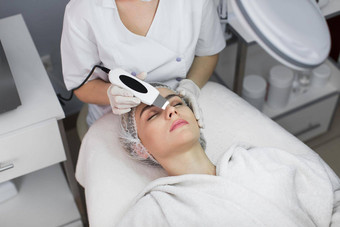 皮肤护理特写镜头美丽的女人接收超声波空化面部剥超声波皮肤清洗过程美治疗美容美水疗中心沙龙