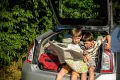 可爱的男孩坐着车树干假期父母孩子们坐着车检查地图夏天打破学校家庭旅行车