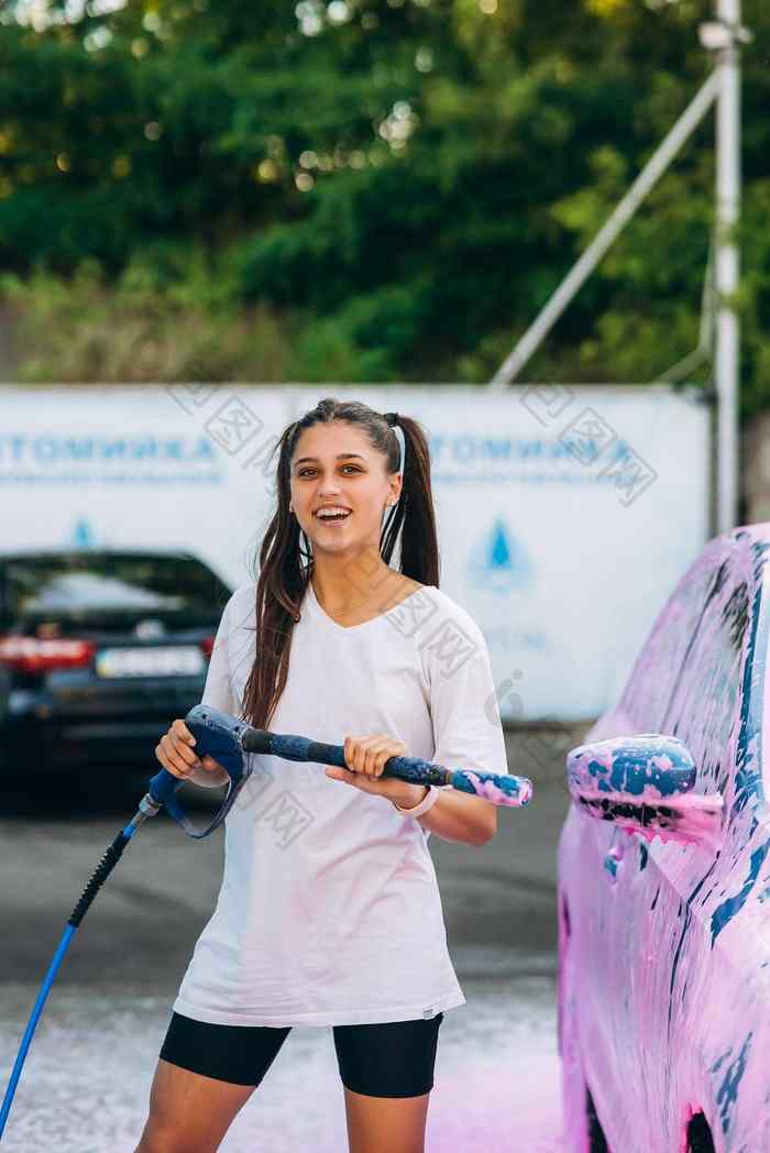 女人高压力软管站车覆盖粉红色的泡沫