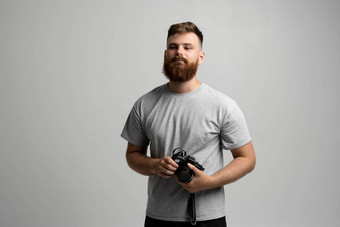 肖像有胡子的专业摄影师灰色t恤数码单反相机相机直相机孤立的灰色的背景