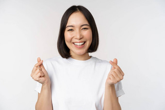 美丽的亚洲女人微笑显示手指心手势穿T恤站白色背景