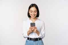 时尚的现代亚洲女孩移动电话应用程序聊天手机微笑站白色上衣工作室背景