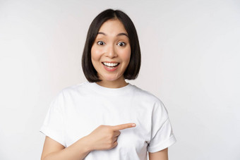 快乐美丽的亚洲女孩显示广告空复制空间指出手指微笑展示横幅公司标志白色背景