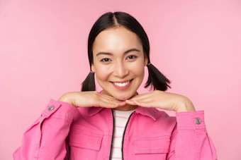 皮肤护理美容概念美丽的亚洲女孩微笑笑显示清洁健康的面部皮肤摆姿势粉红色的背景