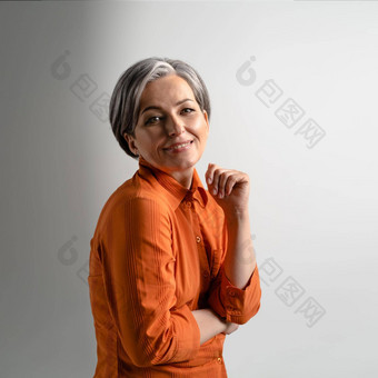 肖像成熟的灰色头发的女人穿<strong>橙色</strong>衬衫幸福的微笑相机漂亮的中期岁的灰色头发的女人<strong>橙色</strong>衬衫孤立的灰色背景