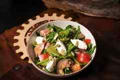 新鲜的素食主义者沙拉蔬菜鱼奶酪蛋南瓜种子芝麻菜白色陶瓷碗皮革围裙前视图