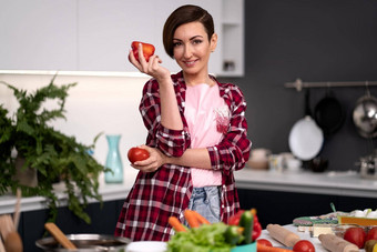 持有贝尔胡椒番茄手家庭主妇穿格子衬衫短发型烹饪蔬菜ragout厨房房子健康的食物首页