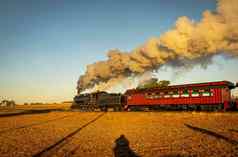 视图古董乘客蒸汽火车吹烟旅行通过日出