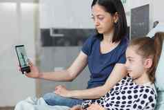 年轻的妈妈。生病的孩子会说话的儿科医生智能手机videocall