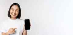 微笑亚洲女人指出手指智能手机屏幕显示应用程序接口移动电话网站站白色背景