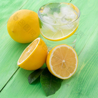 柠檬水玻璃柠檬一半新鲜的叶子绿色表格让人耳目一新冷喝水冰薄荷片柠檬一边视图
