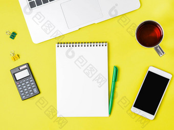 现代有创意的明亮的黄色的办公室桌子上移动PC智能<strong>手机配件</strong>空白记事本页面文本中间前视图