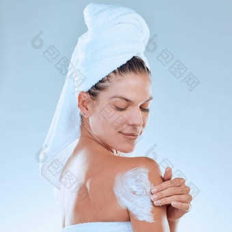 柔滑的皮肤形成<strong>好习惯</strong>工作室拍摄年轻的女人应用保湿霜身体淋浴蓝色的背景