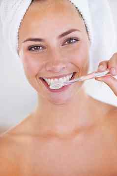 有纪律的刷牙=闪闪发光的牙齿肖像惊人的女人刷牙牙齿