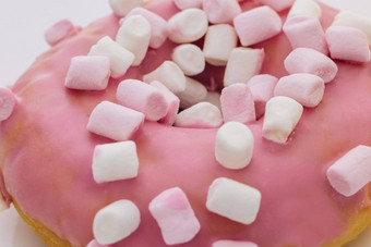 特写镜头拍摄粉红色的美味的美味的甜蜜的甜甜圈色彩斑斓的洒紫色的背景甜点色彩斑斓的磨砂粉红色的甜甜圈