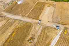 空中照片挖掘机倒沙子卡车建设网站前视图拍摄无人机